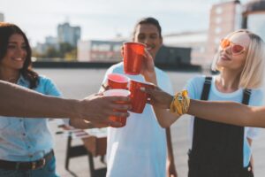 group of friends clinking glasses on alcohol on roof party