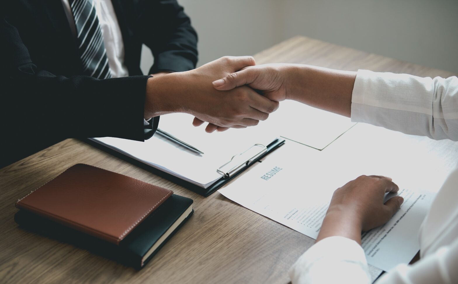 Manager and employee interview concept with handshake after talking about contract signing.