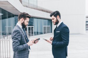 Two contemporary businessman using technological devices